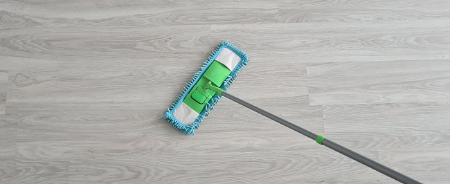 Top view of modern sponge mop used to clean wooden floor with copy space. Cleaning service