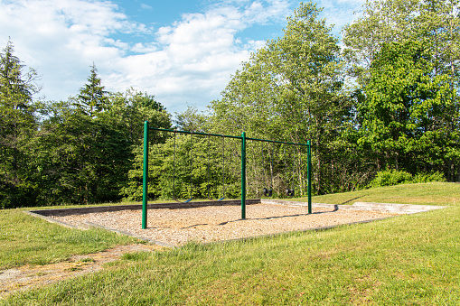 Two-person swing set in a park in sunny day, Canada.