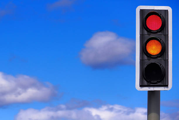 Business Concept: Prepare to Go British traffic lights with the red and amber lights illuminated, with copy space as the blue sky with white clouds. Please see all the different combinations of lights in the following images... blue yellow lights stock pictures, royalty-free photos & images