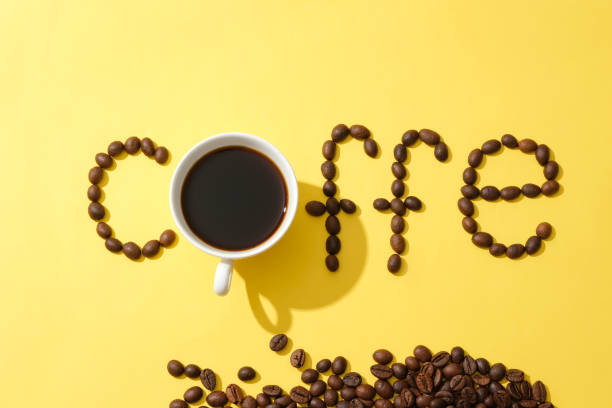 istock Coffee beans are arranged into the word COFFE with a black coffee cup on a yellow background. Creative images for advertising. Copy space. Coffee theme. 1863522957