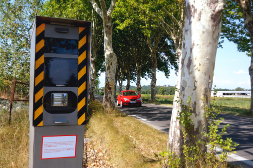 Speed camera on the side of a tree lined road