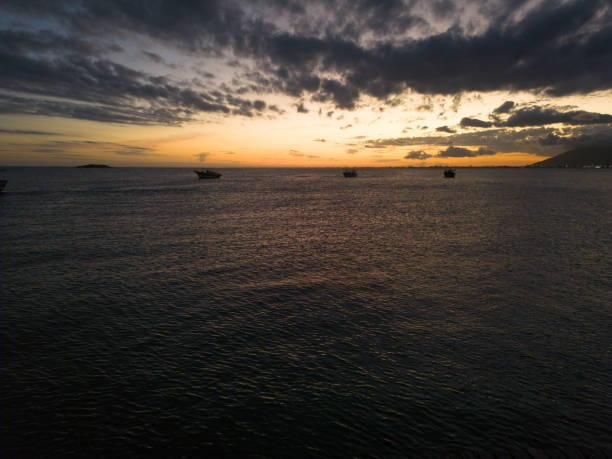 Orange sky after sunset reflecting on the water with anchored fishing boats