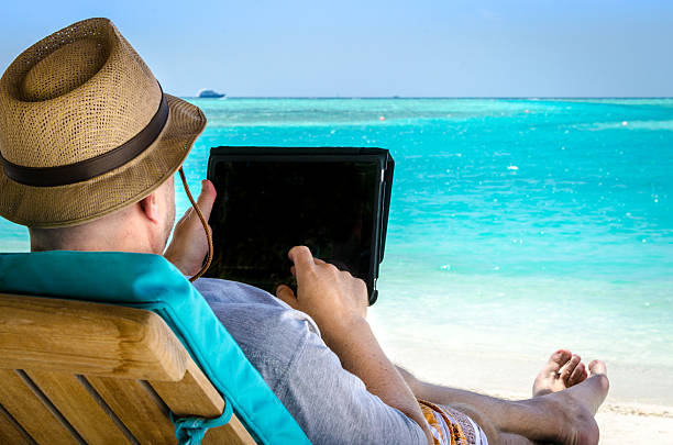istock Man holding tablet during vacation on the beach 186356079