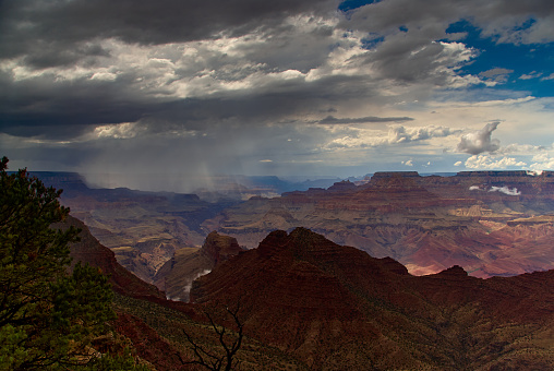 A summer thunderstorm dropping heavy rain over the Grand Canyon, as seen from the south rim near the Desert View Watchtower in Arizona, USA.