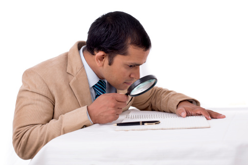 Indian Detective agent searching for something with a magnifying glass. Isolated on white.