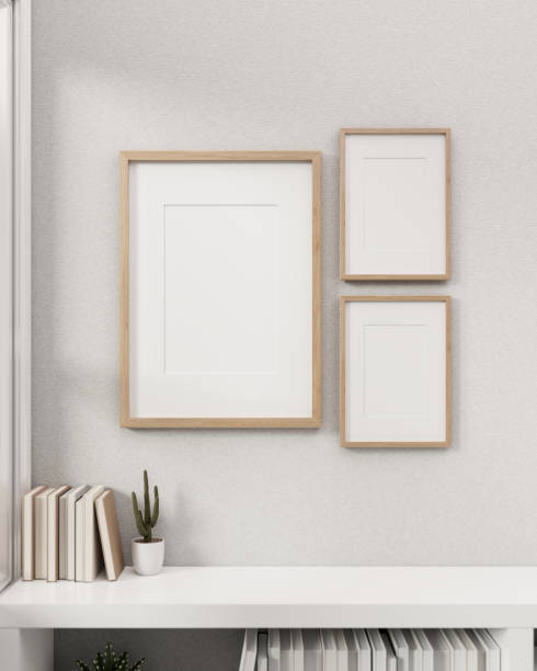 istock Minimal white room with blank picture frames mockup hanging on a white wall above a white bookcase. 1863710907