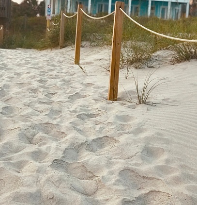 Footprints in sand near sand dune and beach house on Atlantic coast of North Carolina