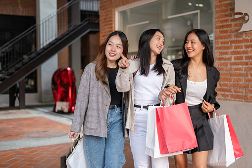 Group of attractive young Asian girls in trendy clothes with shopping bags are enjoying shopping in the city together on the weekend. Flash sale, Mega sale, fashion and lifestyle