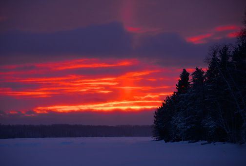 Red orange winter sunset on frozen northern Minnesota Lake