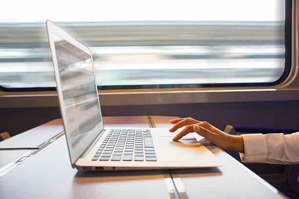 Woman hands typing on a laptop keyboard in the train stock photo