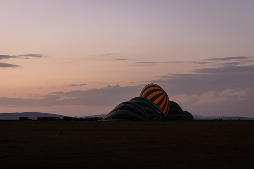 a group of hot air balloons prepare to launch just before the sun comes up in Masai Mara National Reserve, Kenya