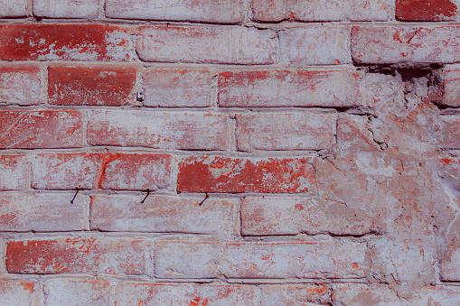 Old red brick wall. Peeled plaster frome the wall.