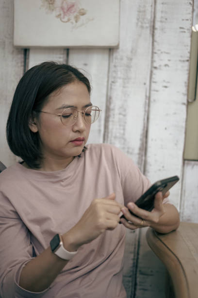 istock Woman sitting looking at mobile phone 1863778728