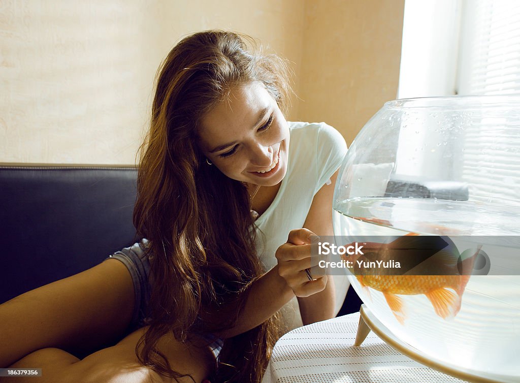 pretty woman playing with goldfish at home, sunlight morning pretty woman playing with goldfish at home, sunlight morning, good mood Fish Stock Photo