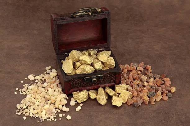 Gold frankincense and myrrh and an old wooden box over brown lokta paper.