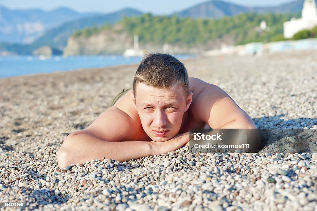 男性に横たわる sunbathes 、岩肌のビーチ - Horizonのロイヤリティフリーストックフォト