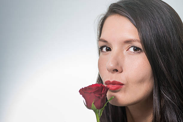 istock attractive woman holding a long-stemmed red rose 186380710