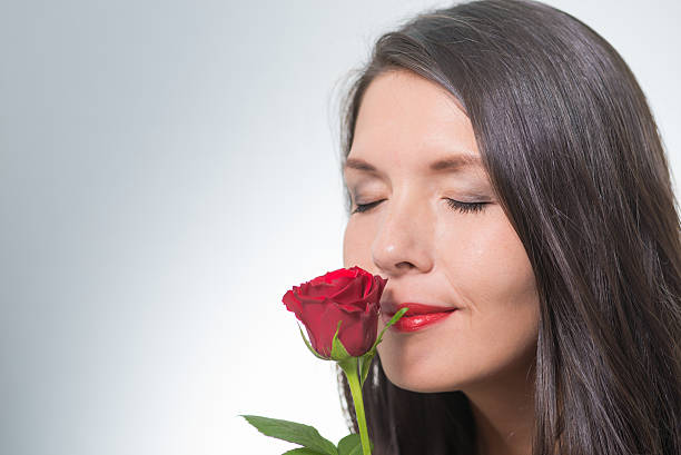 istock attractive woman smells on a long-stemmed red rose 186380841