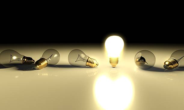 istock One glowing light bulb and the other bulbs in rows 186381354