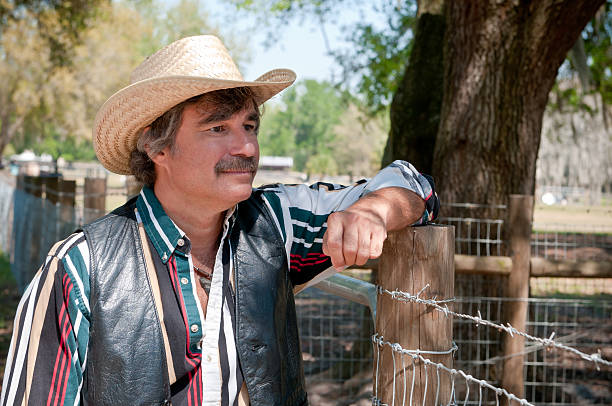 istock Farmer in a cowboy hat looking over his livestock 186381434