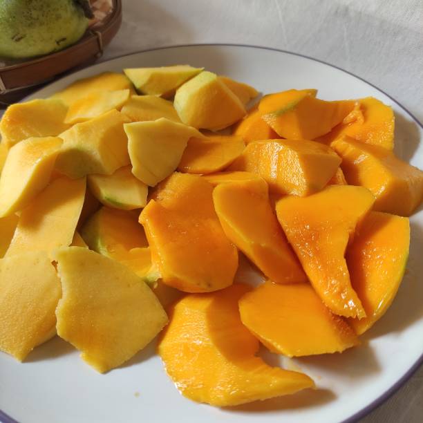 istock Fresh yellow mango slices on a plate on a white table background 1863830711