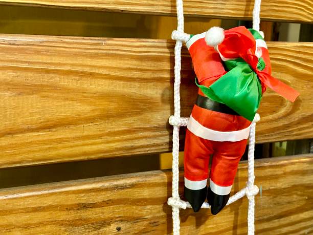 Santa Claus doll is climbing on a wooden wall stock photo