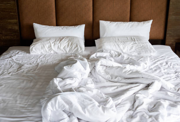 istock Unmade bed with white linens, crumpled empty and messy bed in hotel room. 1863833832