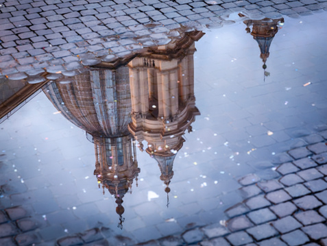 Sant Agnese in Agone lit up by setting sun in Piazza Navona reflected in puddle