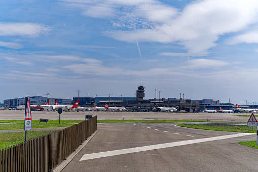 Parked airplanes with air traffic control tower in the background at Zürich Kloten Airport on a sunny summer day. Photo taken July 23rd, 2023, Zurich, Switzerland.