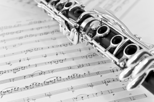 Part of clarinet on sheet music background, black and white.