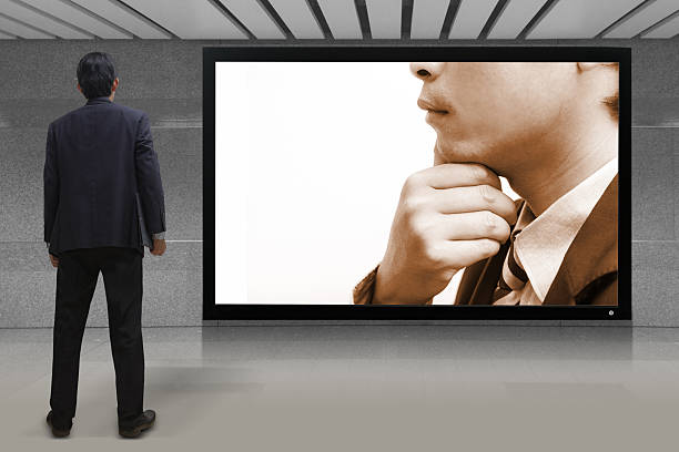 istock Businessman standing looking at the TV screen 186397382