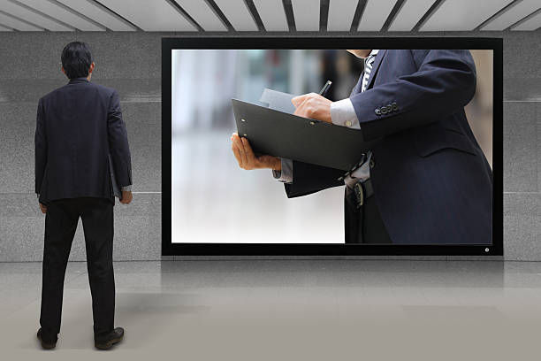 istock Businessman standing looking at the TV screen 186397404