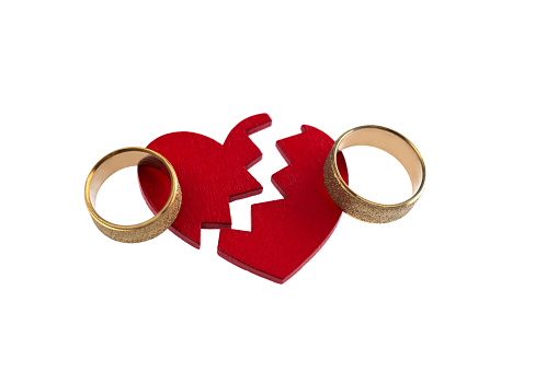 Wedding ring with broken heart on white background