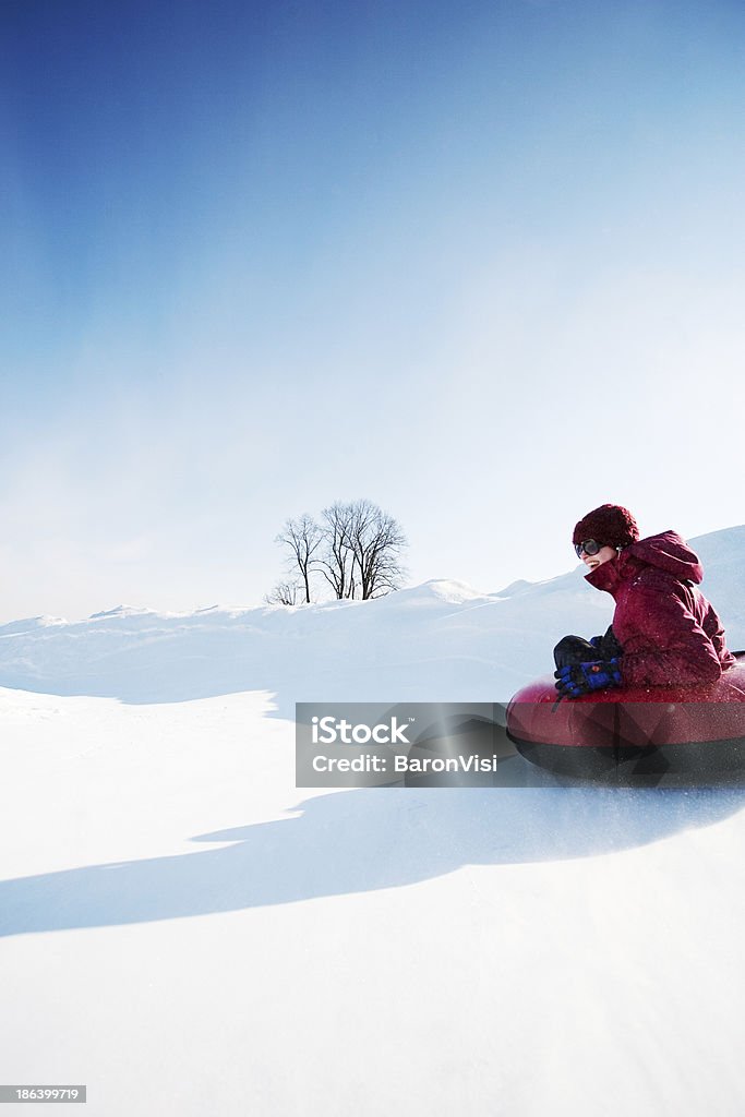 Snow Tubing Young girl enjoying the sunny winter vacation. Tobogganing Stock Photo