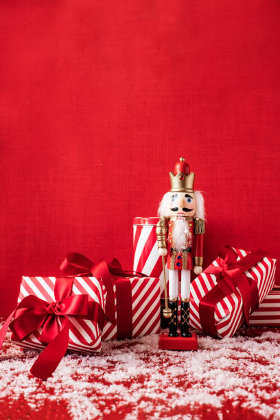 Festive Nutcracker soldier on Christmas background with gift boxes