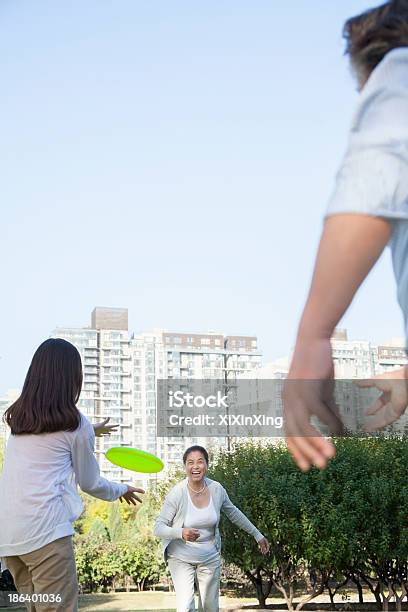 Granddaughter Con Abuelos Jugando Frisbee In The Park Foto de stock y más banco de imágenes de 14-15 años