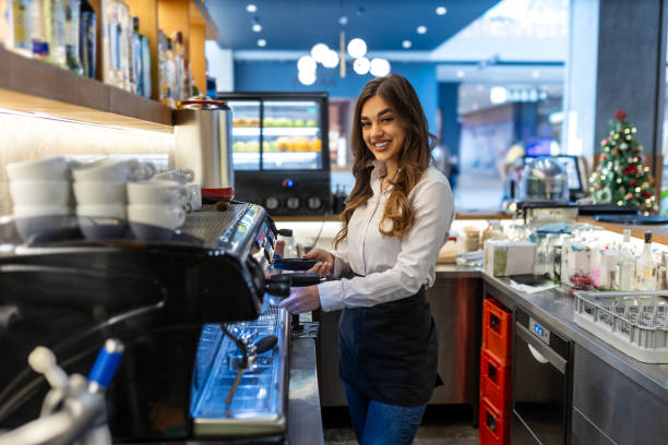 istock Smiling cute woman, barista working with coffee machine, prepare cappuccino, using steamer at cafe counter. 1864011907