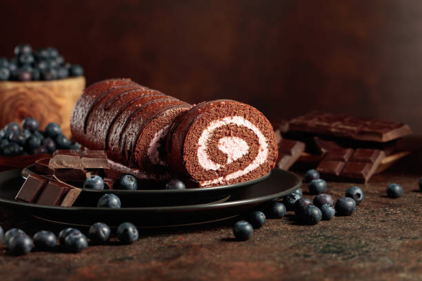 Chocolate roll cake with blueberries and a broken chocolate bar.