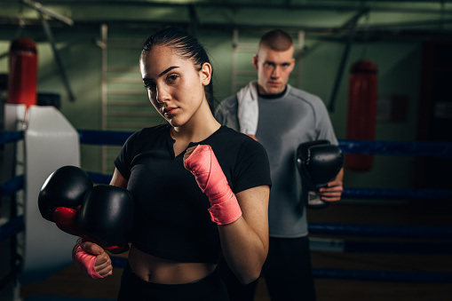 A beautiful determent woman boxer is looking at the camera after a hard training