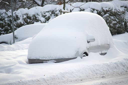 Winter's day with multiple cars, some cars are almost entirely buried by the snow