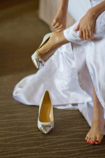 Asian bride putting on shoes on wedding day.