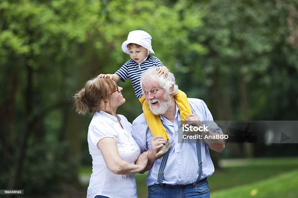 Outdoor fun Little boy having fun with his grandparents in park Picking Up Stock Photo