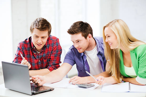 istock smiling students looking to laptop at school 186408181