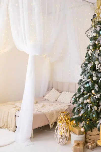 Bedroom in bright colors, decorated for the Christmas holidays. A four-poster bed next to a Christmas tree