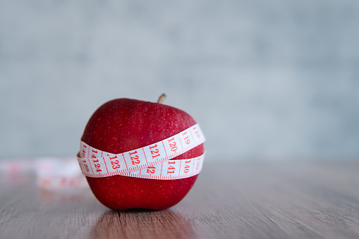 Closeup image of apple and measuring tape. Copy space for text. Diet, healthy eating, weight loss concept.