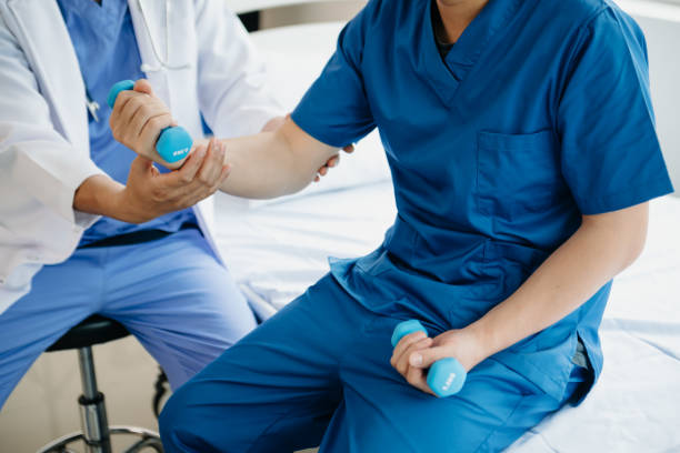 istock Asian physiotherapist helping male patient stretching arm during exercise correct with dumbbell in hand during training hand  in hospital 1864127095
