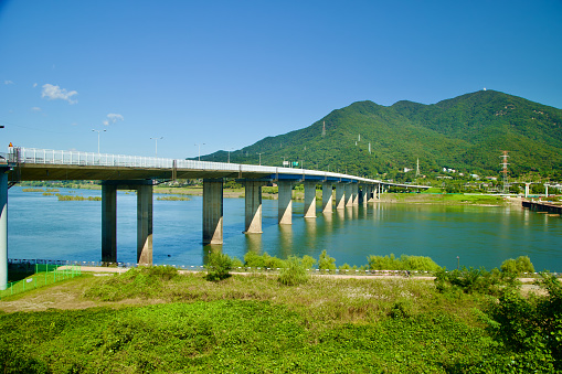 Hanam City, South Korea - October 1, 2023: Paldang Bridge spans the Han River under blue skies, Yebongsan Mountain towering in the distance, entering Namyangju City.