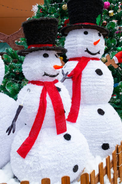 istock two snowmen nearby fir-tree at vertical composition 1864139960