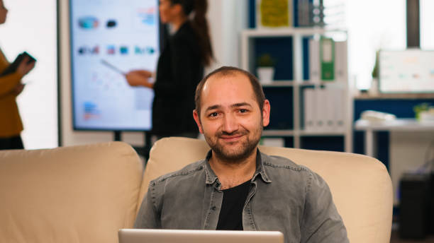 istock Manager sitting on couch in front of camera smiling 1864154661