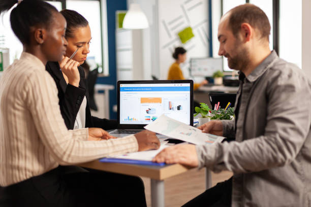 istock Busy multicultural, diverse employees analysing annual financial statistics 1864169926